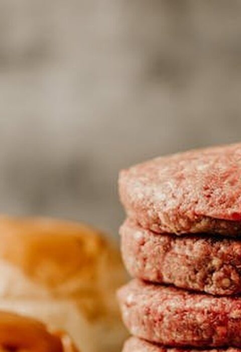 Stack of raw handmade burger patties with brioche buns