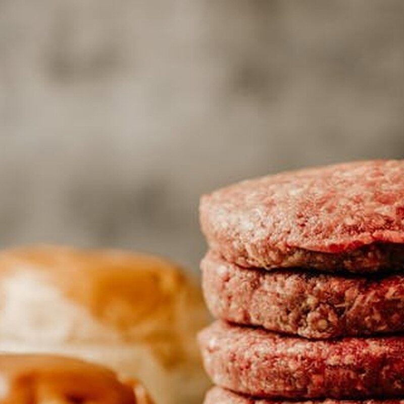 Stack of raw handmade burger patties with brioche buns