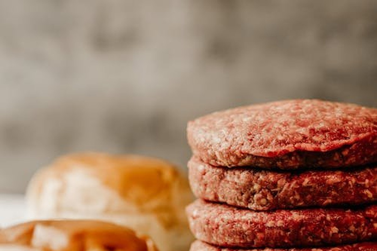 Stack of raw handmade burger patties with brioche buns