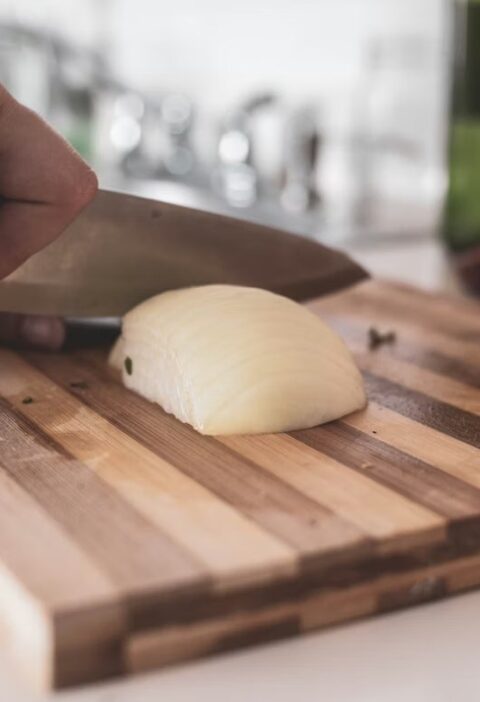 Cutting an onion on a wooden cutting board with chef knife