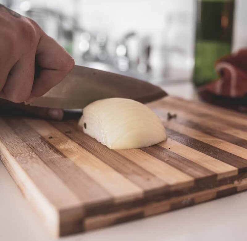 Cutting an onion on a wooden cutting board with chef knife