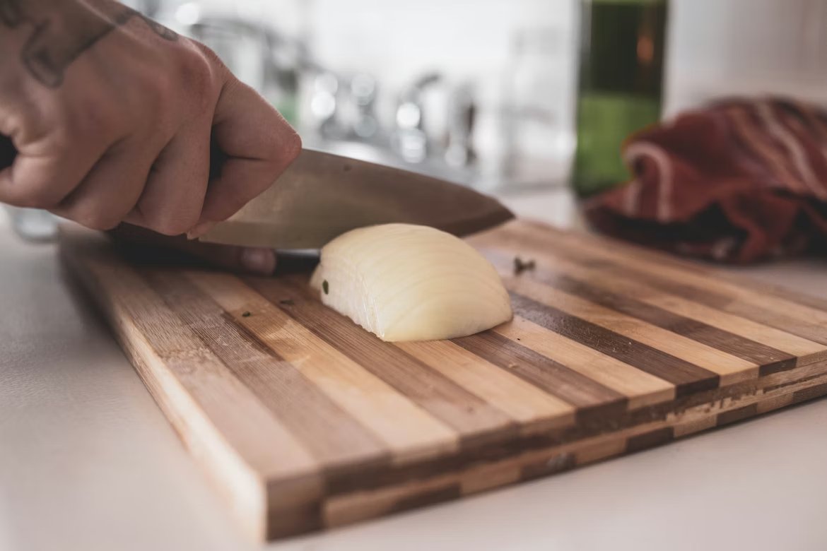 Cutting an onion on a wooden cutting board with chef knife