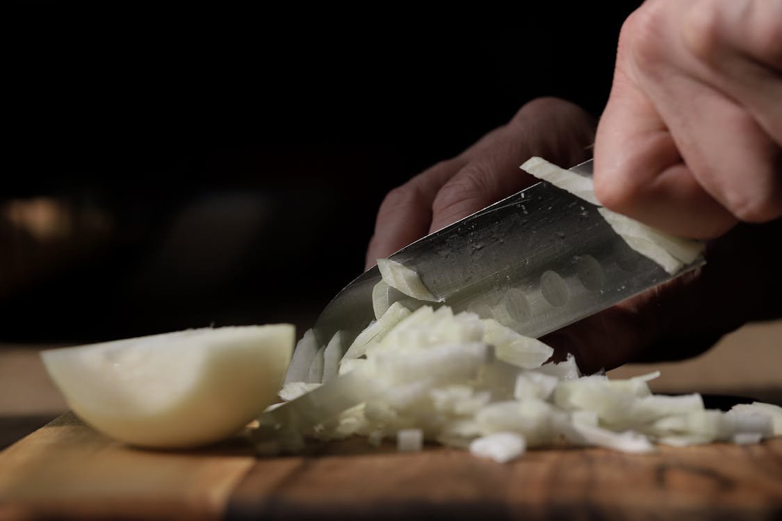 Dicing an onion with a chef knife on a cutting board