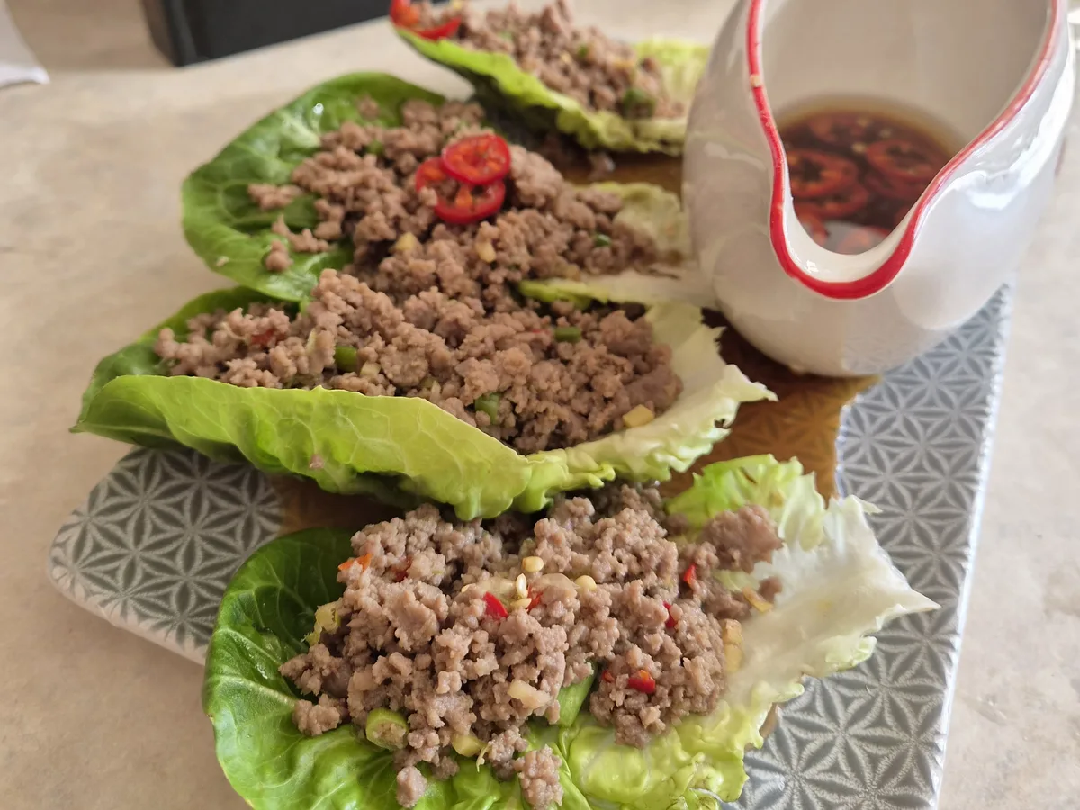 Chilli beef lettuce wraps on a grey plate with chilli sauce jug, cooked and photographed by reader Alex Sunins