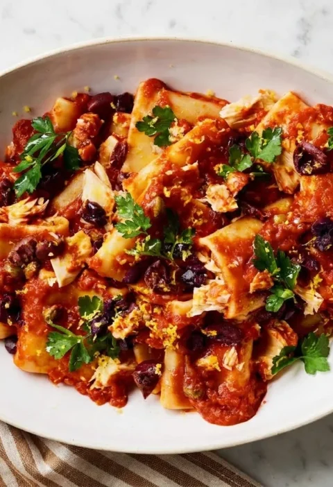 Gordon Ramsay tuna puttanesca with paccheri pasta, black olives, capers, lemon zest and parsley in a white oval dish